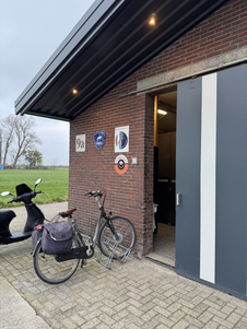 Naast de deur naar de kantine, zit de fietsenstalling en de deur naar de manege paarden.